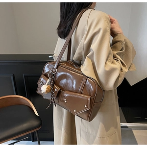 Vue détaillée du sac à bandoulière en cuir marron avec poches multiples et breloque baseball