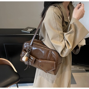 Détail d'un sac à épaule en cuir PU marron brillant avec poches et breloque sport