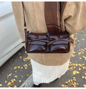 Detail of dark brown glossy PU leather bag with bow knots and dual front pockets