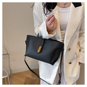Detail of black pebbled leather tote bag with gold U-shaped buckle and adjustable strap
