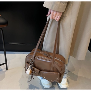Détail du sac à main en similicuir marron avec plusieurs poches et breloque baseball