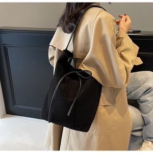 Detail of black suede shoulder bag featuring an elegant decorative bow knot on the side