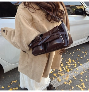 Detail of dark brown bow-knot shoulder bag in glossy patent leather shown outdoors