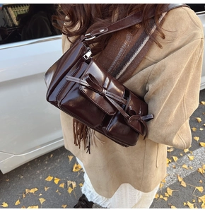 Detail of dark brown vintage PU leather underarm bag with bow-knot pocket outdoors