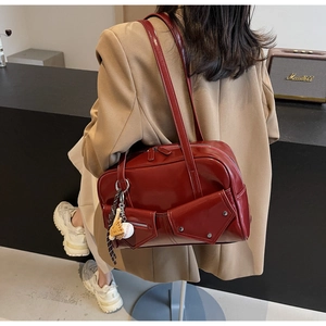 Détail d'un sac cabas bordeaux en cuir verni avec breloques de baseball et rivets