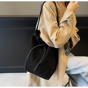 Detail of black suede tote bag with drawstring design and soft matte finish texture