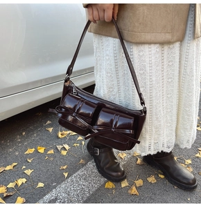 Detail of burgundy patent leather bag with twin bows on a background of autumn leaves