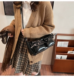 Detail of black glossy PU leather bag featuring front pockets and chic bow accents