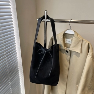 Minimalist black nylon bucket bag with leather strap displayed on metal rack