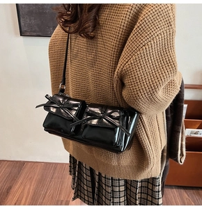 Detailed view of black patent leather bag with bow pockets and sleek shoulder straps