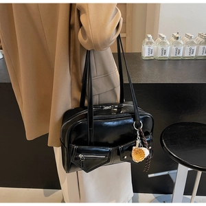 Détail du sac Boston noir en similicuir brillant avec poches avant et breloque biscuit