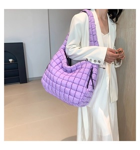 Detail van een grote paarse gewatteerde shopper met puffer-textuur en brede riem