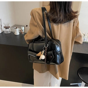 Détail d'un sac Boston en cuir verni noir brillant avec des breloques de baseball sport