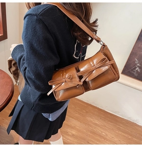 Detailed view of brown PU shoulder bag featuring twin front pockets with stylish bow accents