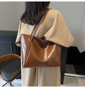 Dettaglio del logo VVGONGZYD goffrato sulla borsa tote in pelle marrone lucida