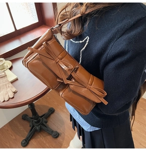 Close-up of caramel brown glossy PU leather shoulder bag with double bow decoration