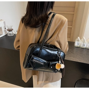 Détail du sac à épaule noir en similicuir avec poches multiples et breloque de baseball
