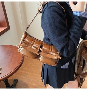 Close-up of vintage brown PU leather shoulder bag with bow details and front pockets