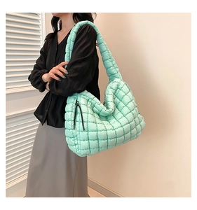 Detail van mintgroene gewatteerde bubble tas met oversized zachte textuur en brede schouderband