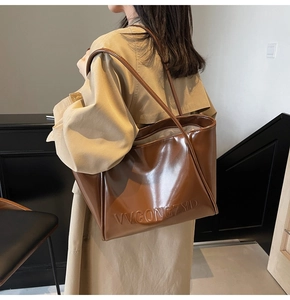 Dettaglio della grande borsa tote marrone lucida con trama a rilievo e spalline sottili