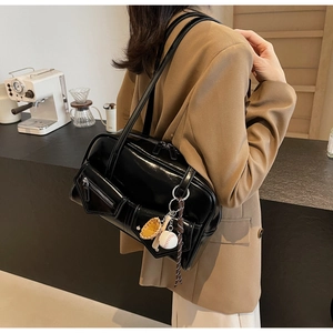 Détail du sac à main noir brillant en similicuir avec breloque baseball et poche zippée