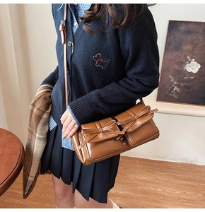 Close-up of vintage brown PU leather bag with decorative bows and dual front pockets