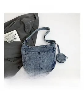Détail du sac bandoulière en denim bleu délavé avec sangle ajustable et porte-monnaie