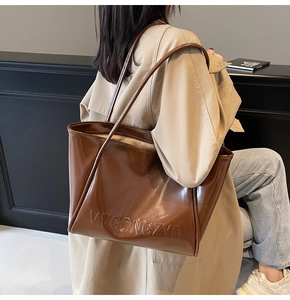Dettaglio di una grande borsa tote in vernice marrone con logo VVGONGZYD per donna