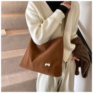 Detail of a brown PU leather shoulder bag with a silver heart-shaped metal clasp buckle