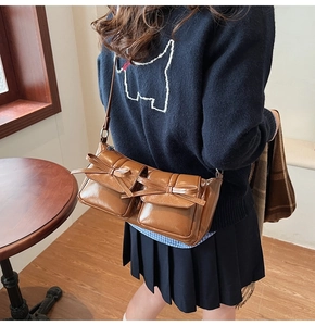 Detail view of brown PU shoulder bag featuring twin bow-decorated front flap pockets