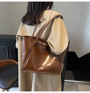 Dettaglio della borsa tote marrone caramello con logo VVGONGZYD goffrato in pelle PU