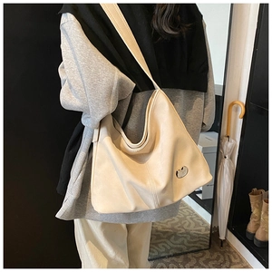 Detailed close-up of cream-colored Hobo bag showing soft PU leather and silver cat logo