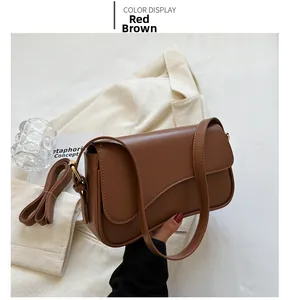 Detail view of red-brown PU leather crossbody bag with dual straps and curved flap design