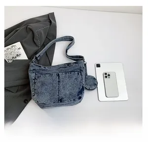 Gros plan d'un sac à bandoulière en denim délavé avec un petit pendentif circulaire