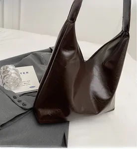 Détail d'un sac cabas marron foncé en similicuir à texture cirée sur un blazer