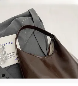 Détail montrant la texture en cuir ciré marron foncé et la poignée de ce sac à main