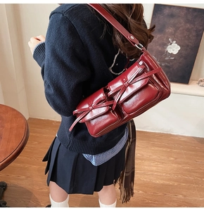 Detail of burgundy PU leather shoulder bag featuring two front pockets with bow accents