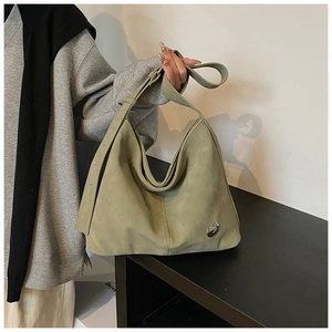 Detail of green suede Hobo bag showing heart logo and adjustable strap holes