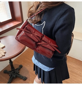 Detail of dark red patent leather shoulder bag with vintage bows and glossy finish