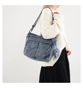 Détail du sac bandoulière en denim avec poches extérieures et petit porte-monnaie rond