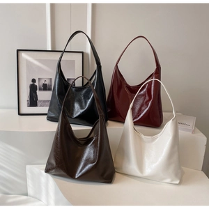 Sacs hobo plissés brillants en quatre coloris disposés sur un présentoir blanc