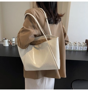 Dettaglio di una borsa tote in pelle PU beige lucida con logo in rilievo 3D e tracolla