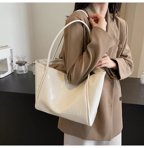 Dettaglio della borsa tote in pelle color crema con logo VIVIGONGZYD goffrato sulla spalla