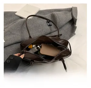 Spacious interior of a dark brown glossy shoulder bag showing daily essentials and lining