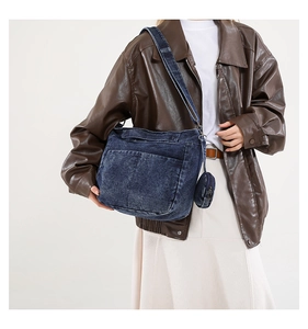 Détail du sac bandoulière en jean bleu avec large sangle et mini porte-monnaie rond