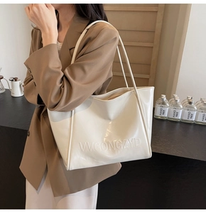 Dettaglio di una borsa tote bianca lucida con lettere in rilievo e doppi spallacci