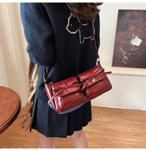 Detail view of deep red PU leather shoulder bag with vintage bow pockets on model