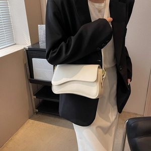Minimalist beige crossbody bag with wavy asymmetric flap and golden metal clasp for women