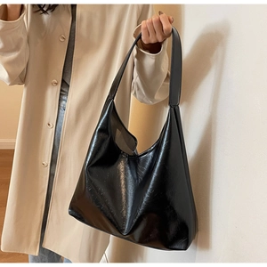 Détail d'un grand sac cabas noir brillant avec une texture vintage en cuir ciré
