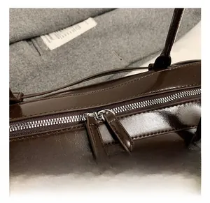 Detail of the high-quality double metal zippers on this dark brown glossy shoulder bag